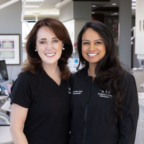 A portrait of board certified orthodontists Dr. Mairead O'Reilly and Dr. Riddhi Desai standing together in their orthodontic office in Annapolis, MD